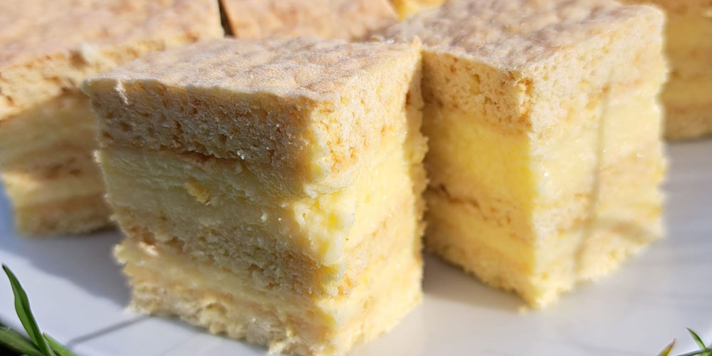 Foto des Rezeptes der Honigschnitten, zu sehen sind klein geschnittene Stücke, oben und unten lockerer Teig mit einer cremig-gelben Fülle in der Mitte