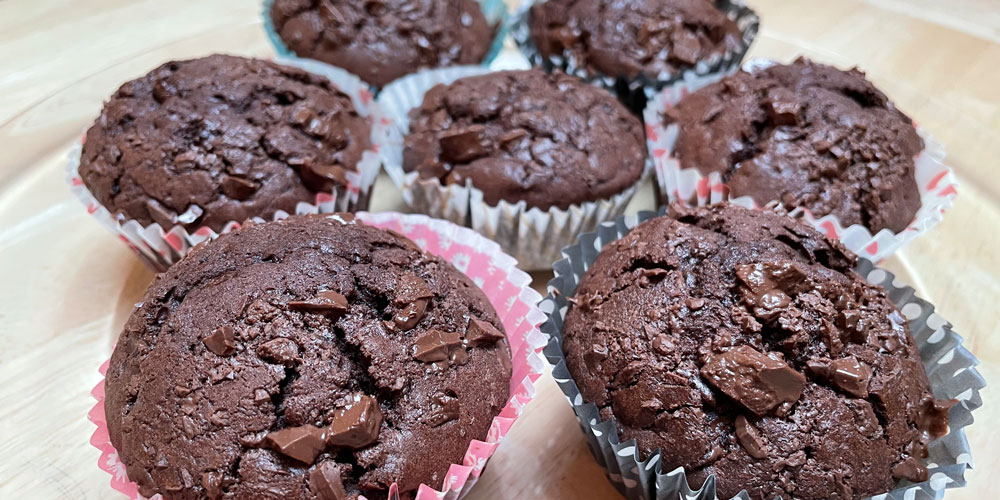 Foto zum Rezept Schokomuffins mit Honig, präsentiert in kleinen bunten Muffenförmchen auf einem Tisch